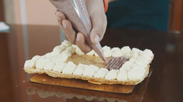 Пекарь мужские руки сжимает заполнение крем из рукава на слое торта
 - Кадры, видео