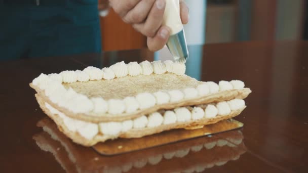 Baker hombre musculoso aprieta soplos de crema batida en línea en la capa de pastel
 - Metraje, vídeo