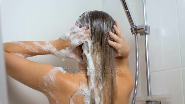 Zeitlupenaufnahmen einer brünetten Frau, die sich Shampoo aus den Haaren wäscht - Filmmaterial, Video