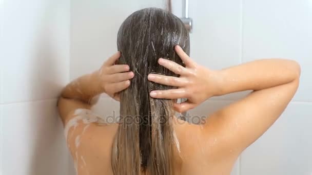 Rear view slow motion footage of sexy woman washing hair at shower - Video