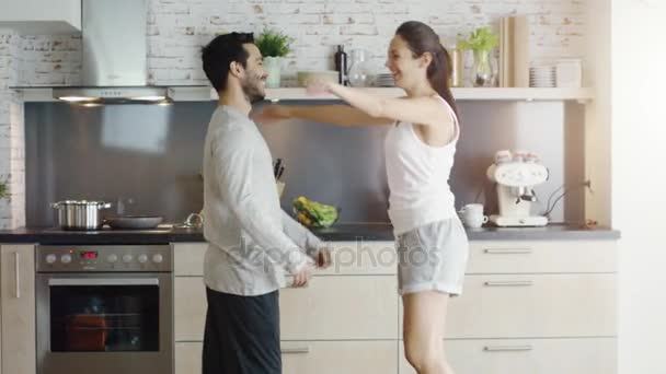 Happy Couple on the Kitchen. Girl Jumps into Guy's Arms. - Felvétel, videó