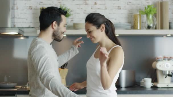 Happy Young Couple Dances in the Kitchen and then Embracing. In Slow Motion. - Video