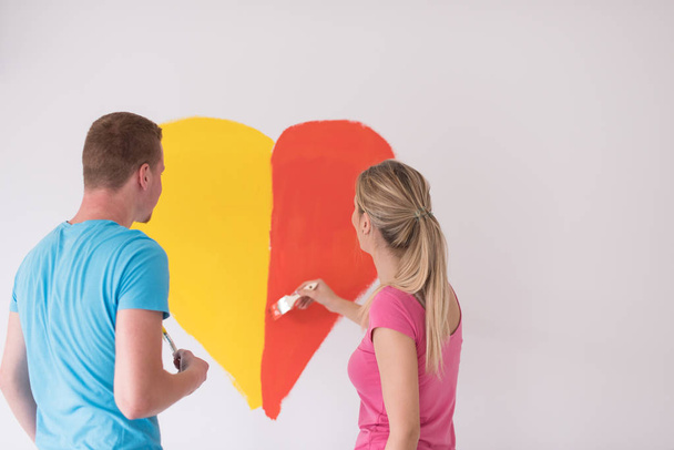 couple are painting a heart on the wall - Φωτογραφία, εικόνα