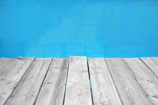 Deski drewniane molo przeciwko niebieski woda - Zdjęcie, obraz
