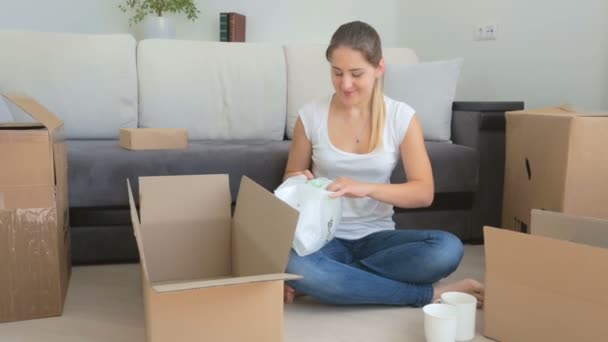 Hermosa mujer joven empacando cosas del viejo apartamento en las cajas de cartón
 - Imágenes, Vídeo