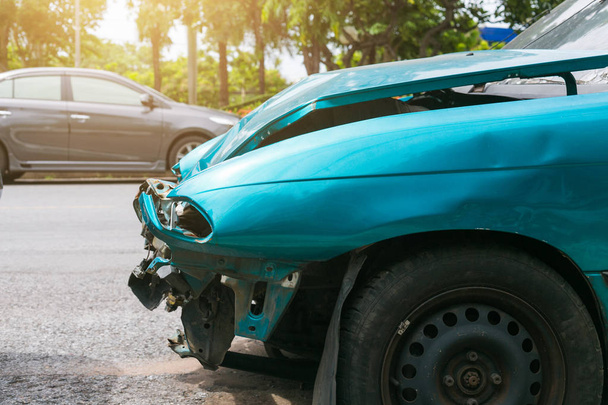 Voorkant van groene auto beschadigd raakt door een ongeval op de weg. - Foto, afbeelding