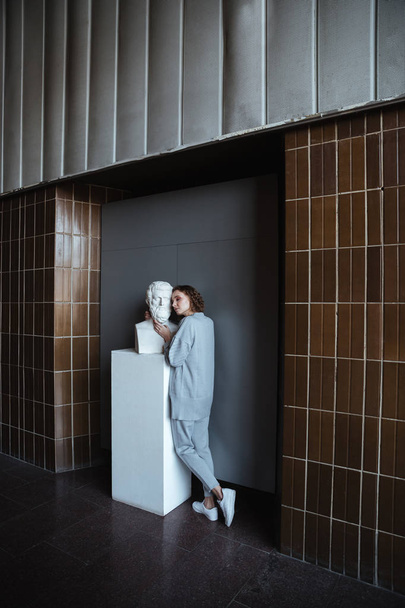 Young woman touching marble bust - 写真・画像