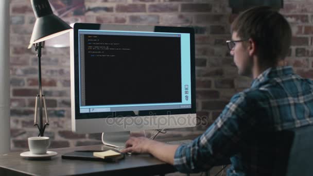 Nuori valkoihoinen ohjelmoija työskentelee tietokoneella hänen sisätoimistossaan
. - Materiaali, video