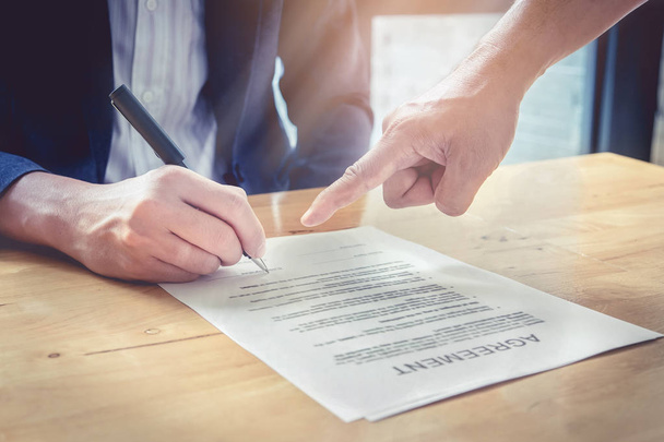 Крупный план агентов и бизнесмена, указывающих на подписание контракта
 - Фото, изображение
