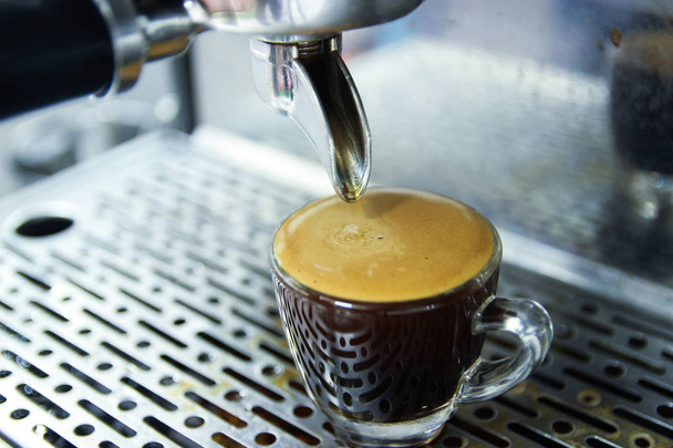 Zamknięty espresso, którego strzał były spilśniania w Pucharze z ekspresem do kawy. Ten strzał kawy zostały wykonane z ziaren kawy najlepsze z najlepszych gospodarstwa. Przejdź za pomocą standardowej procedury. Pieczenia i szlifowania przez pro. - Zdjęcie, obraz