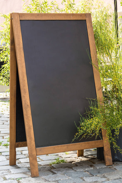 Black chalkboard stand on wood for a restaurant menu in the stre - Photo, Image