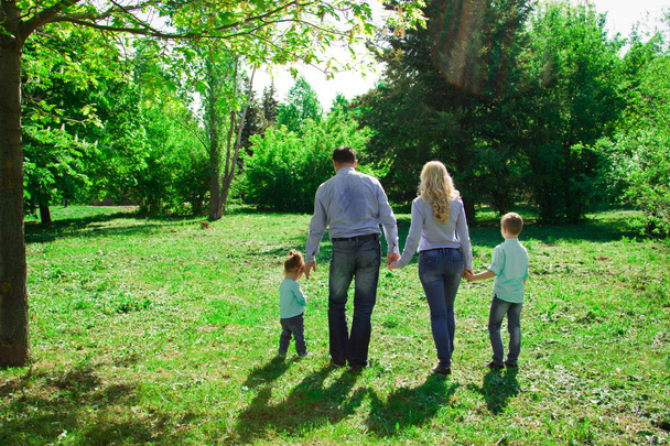 A family of four walks in the park.  - Foto, Imagem