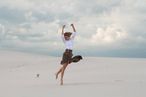 La chica está volando felizmente en el desierto
 - Foto, Imagen