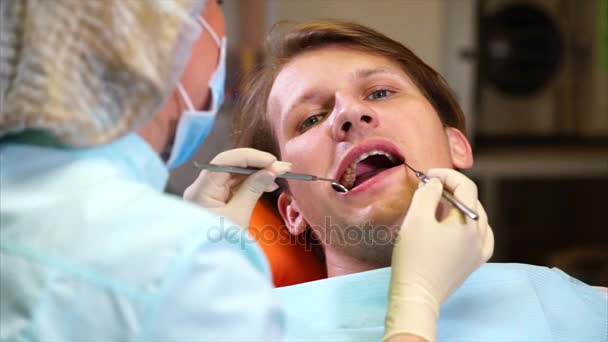 Kobiece dentysta sprawdza jamy ustnej pacjenta z lusterko dentystyczne - Materiał filmowy, wideo