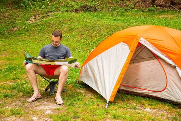 Man met kaart naast Tent kamperen in de natuur - Foto, afbeelding