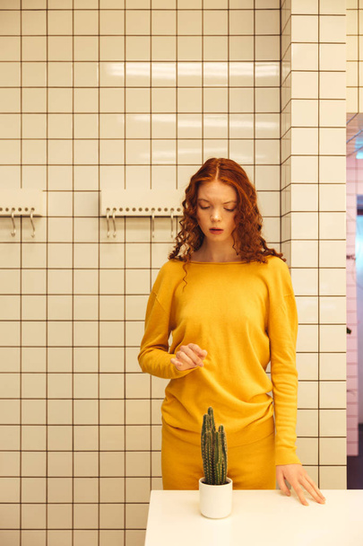 Concentrated young redhead curly lady standing in cafe - 写真・画像