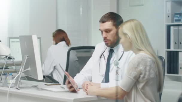 V ordinaci lékař konzultuje krásná mladá žena s pomocí Tablet. Jejich vzhled a obrazovky a úsměv. - Záběry, video