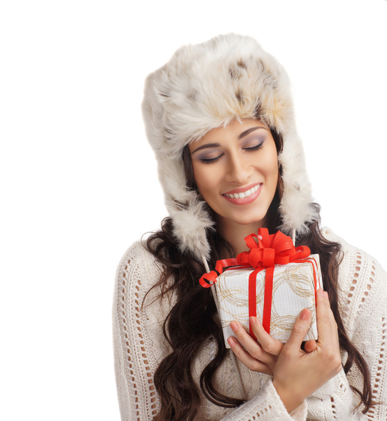 Young and beautiful woman holding a nice Christmas present over white background - Фото, зображення