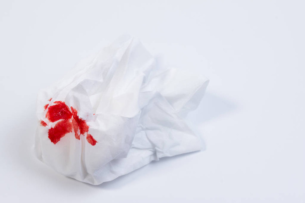Wundblut, Blut auf Seidenpapier auf weißem Hintergrund. Nasenbluten oder Epistaxis Behandlung Blut in Seidenpapier. Gesundheitsmedizin. - Foto, Bild