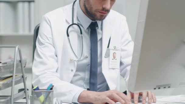Close-up of a Male Doctor is Working at His Desk. He Uses Personal Computer and Documents. - Materiaali, video