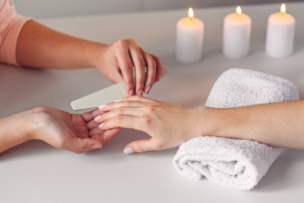 Spa salon.  Beautiful woman hands having nail filing with nail file by manicurist. Cosmetic procedure, manicure on female hand. - Valokuva, kuva