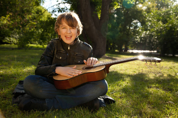 adolescente al aire libre con una guitarra, un libro y una manzana al atardecer en el parque divirtiéndose
 - Foto, imagen