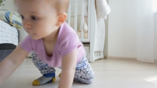 Dolly shot of cheerful baby boy holding toy and crawling on floor towards the camera - Video