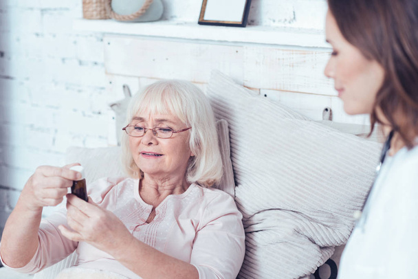 Helpful social work assistant offering medicament to pensioner at home - Zdjęcie, obraz