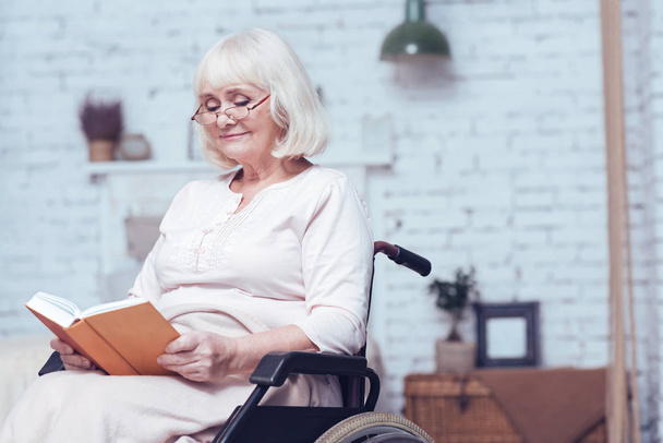 Content retired disabled woman reading book at home - Foto, Bild