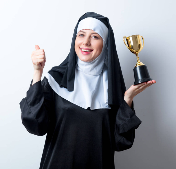 monja con copa de trofeo dorado
  - Foto, Imagen