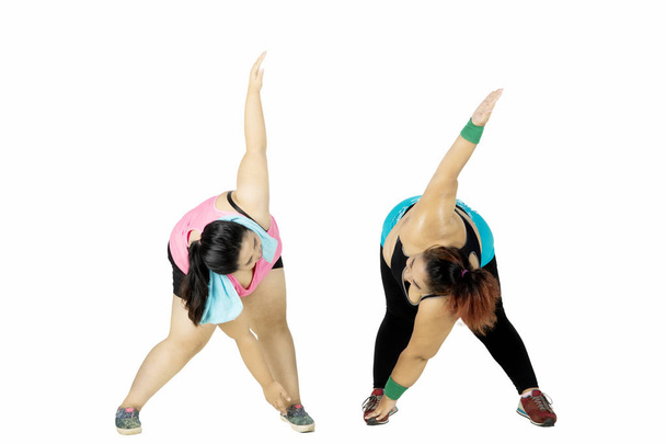 Two overweight women doing stretching on studio - Foto, imagen