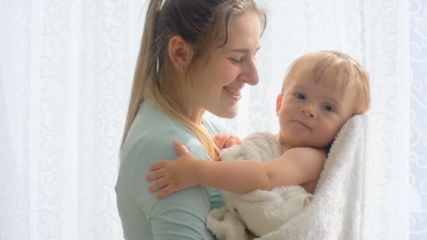 Slow motion close-up video van moeder haar zoon baby knuffelen op zonnige ochtend - Video