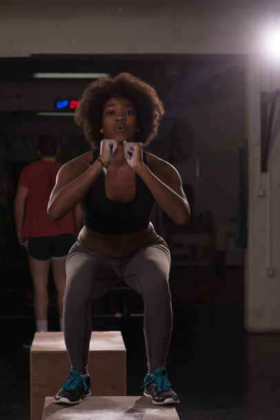 black female athlete is performing box jumps at gym - Foto, Imagem