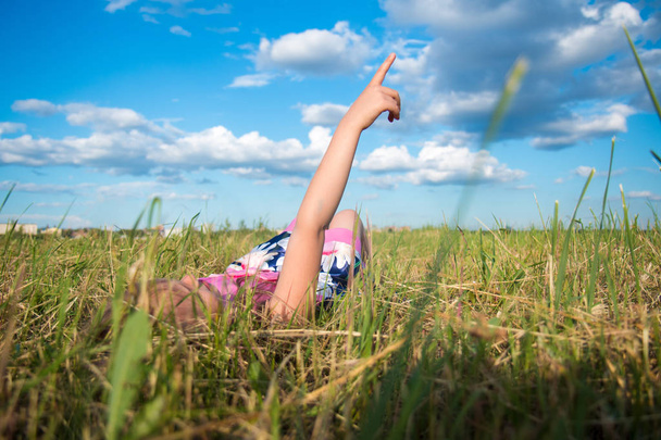 Happy dreamy girl lies in the park on grass and shows on clouds, dreams - Fotografie, Obrázek