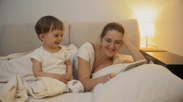 4 k video van schattige babyjongen glimlachen en lachen tijdens het kijken naar tekenfilms op digitale tablet voordat je slapen - Video