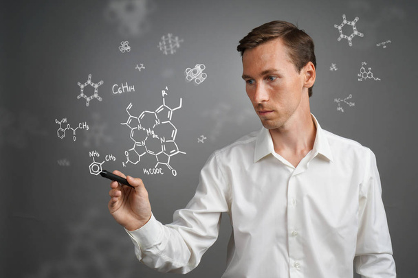 Hombre científico con lápiz o lápiz que trabaja con fórmulas químicas sobre fondo gris
. - Foto, Imagen