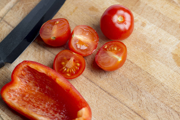 Black ceramic knife on a wooden Board with cherry tomatoes. - 写真・画像