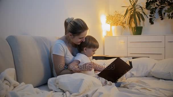 4k footage of mother reading book to her baby son - Filmati, video
