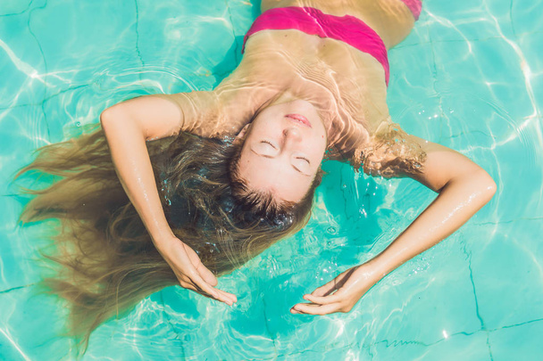 young woman floating in pool - Φωτογραφία, εικόνα