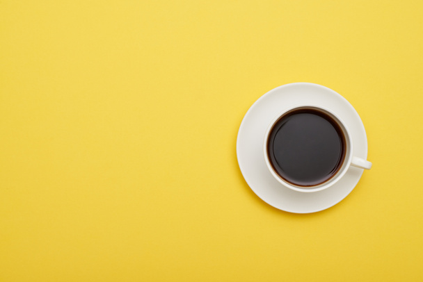 Flat lay of yellow desk with cup of aromatic coffee - Foto, afbeelding