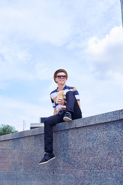 Stylish young man having lunch while resting outdoors in front o - Fotografie, Obrázek