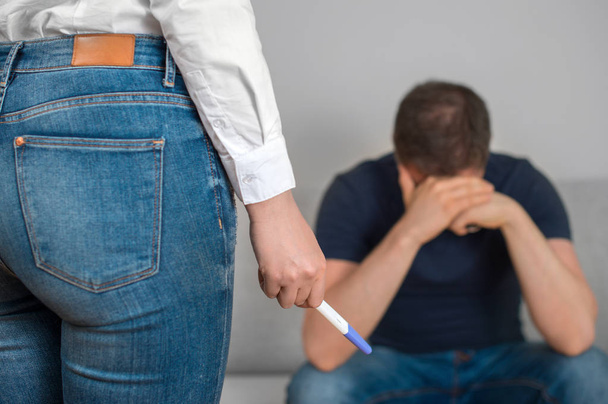 Girl with pregnancy test in front of sad boyfriend. - Photo, Image