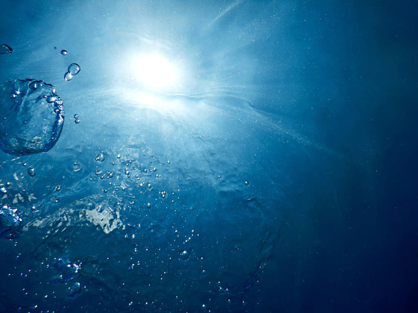 Unter Wasser sprudelt Sonnenlicht durch die Wasseroberfläche. Unterwasserwelt - Foto, Bild