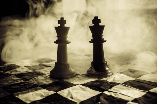 Šachy desková hra koncept podnikatelských nápadů a precizní strategie a soutěž myšlenek. Šachové figury na tmavém pozadí se kouře a mlhy a okno se sluneční světlo. - Fotografie, Obrázek