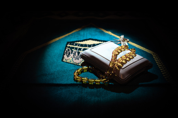 Heilige Quran met parels op de mat van een gebed, moslim Tasbih is een string van gebed kralen die traditioneel door moslims samen met de Koran gebruikt wordt. Ramadan vakantie concept - Foto, afbeelding