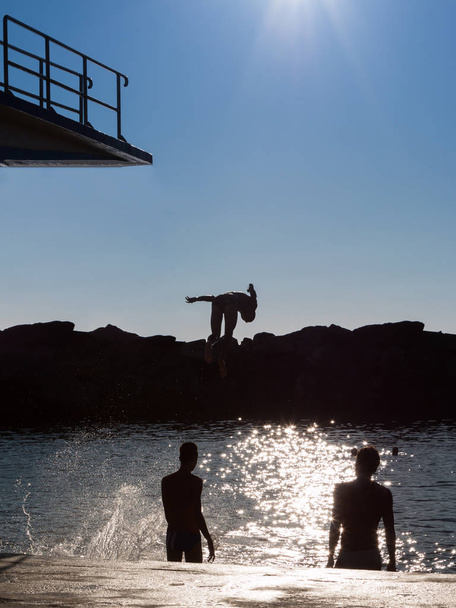 Ugrás magas tábláról vízbe gyermek: szórakoztató nyáron - Fotó, kép