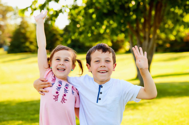 Happy little siblings embracing and waving hands - Фото, зображення