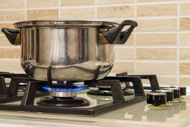 Kovový vaření hrnec stojící na kuchyň sporák s plamenem. - Fotografie, Obrázek