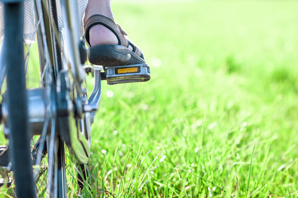 Womans stopę na pedał rowerowy na zbliżenie zielony trawa - Zdjęcie, obraz