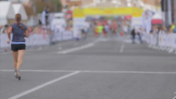 Fuera de foco de los corredores que van a la línea de meta en maratón de la ciudad
 - Metraje, vídeo